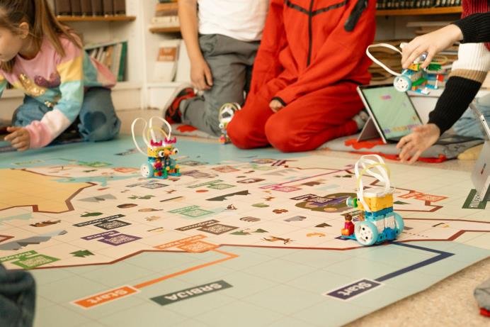 Djeca zajedno programiraju robota na velikoj mapi